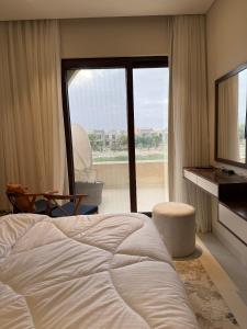 a bedroom with a bed and a large window at Zill Hawana in Ma‘mūrah
