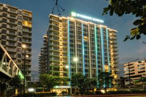 a tall building with lights on it at night at Wyndham Garden Manila Bay in Manila