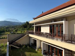 a house with a balcony with mountains in the background at Qiana House in Manggis