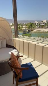a room with a balcony with a bed and a chair at Zill Hawana in Ma‘mūrah