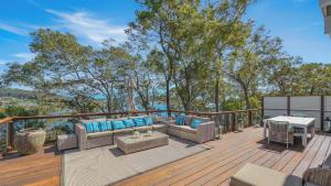 a patio with couches and a table on a deck at 'Hampton Cottage' by HolidayCo in Pretty Beach