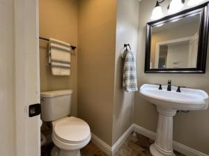 a bathroom with a toilet and a sink and a mirror at Fantastic 6 bedroom, 4 & Half bath home (4 master Suites), pool home in Anaheim