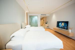 a white bedroom with two beds and a flat screen tv at 玉恒酒店 in Sihui