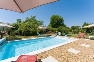 a pool with chairs and umbrellas in a yard at Gîte le Petit Luberon - Lisianthus in Cabrières-dʼAvignon