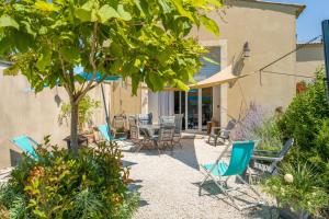 a patio with chairs and a table and a tree at Gîte le Petit Luberon - Lisianthus in Cabrières-dʼAvignon