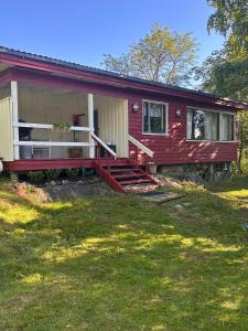 a red house with a porch and a yard at En mysig liten Stuga nära naturen och havet in Västlax