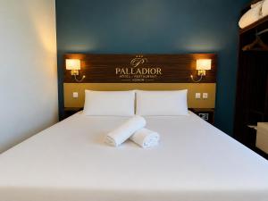 a bed with two rolled towels on top of it at Hôtel Le Palladior Voiron in Voiron +13 photos