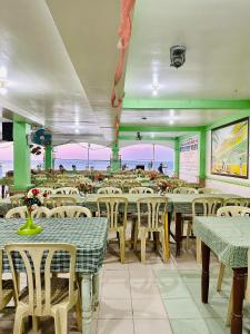 a dining room with tables and chairs and the ocean at White Beach Resort Bar & Restaurant in Puerto Galera