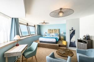 a bedroom with blue walls and a bed and chairs at Baya Hotel in Capbreton