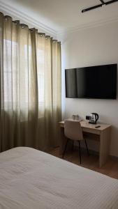 a bedroom with a bed and a desk with a television at Sarai-Batu Guest House in Atyrau