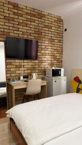 a bedroom with a bed and a desk with a tv on a brick wall at Sarai-Batu Guest House in Atyrau