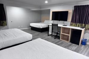 a hotel room with two beds and a desk with a television at Travelodge by Wyndham Redding CA in Redding +46 photos