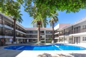 an apartment building with a swimming pool and palm trees at Comfort Inn Hermosillo Pitic in Hermosillo