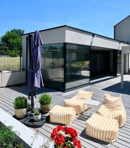 a patio with two chairs and an umbrella and flowers at Architect-Designed Villa with Heated Indoor Pool in Oslip +53 photos