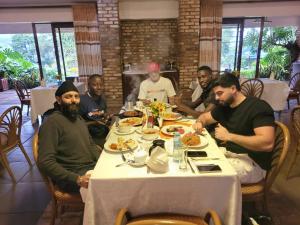 a group of men sitting at a table eating food at WYCLIFF BnB in Chabahinga