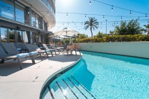 a swimming pool with chairs and a building at Calipolis in Sitges