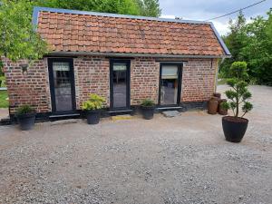 a small brick house with potted plants in front of it at Le clos d'oli in Wamin