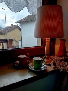 two coffee cups and a lamp on a window sill at il Bucaneve in Norcen