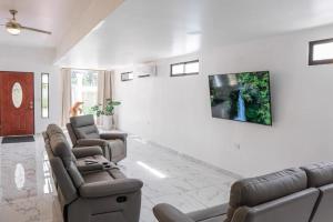 a living room with couches and a tv on a wall at Lions Houses in Parrita