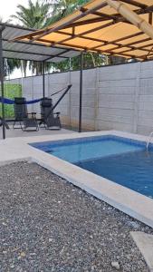 a swimming pool with a pergola and two chairs at Lions Houses in Parrita +3 photos