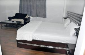 a bedroom with a white bed and a couch at Hotel Aam Bagh & Jain Shikanji in Kot Pūtli +2 photos