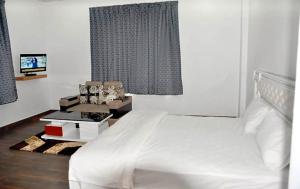 a bedroom with a white bed and a table with boxes at Hotel Aam Bagh & Jain Shikanji in Kot Pūtli