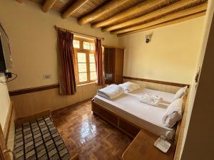 a bedroom with a bed with white pillows and a window at Gangs-Shun Homestay in Leh