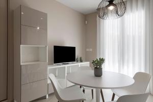 a white dining room with a white table and chairs at Brezza Apartments in Santa Flavia