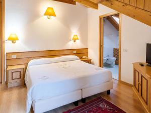 a bedroom with a white bed and a television at Albergo Al Laghetto B&B in Asiago