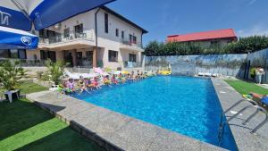 a group of people sitting in chairs by a swimming pool at Motel Didona B in Galaţi