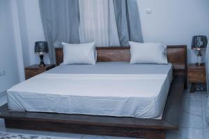 a bedroom with a bed with white sheets and pillows at Appart Congo- Brazza - Av de la paix in Brazzaville