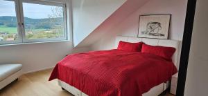 a bedroom with a red bed with a window at Ferienhaus Panoramablick Altfalter in Schwarzach bei Nabburg