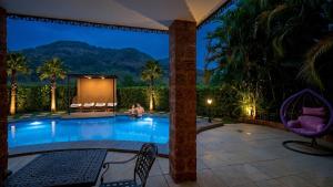 a pool at night with mountains in the background at Nostravila Resort and Spa in Lonavala
