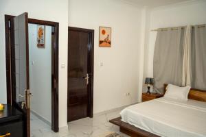 a bedroom with a white bed and a door at Appart Congo- Brazza - Av de la paix in Brazzaville