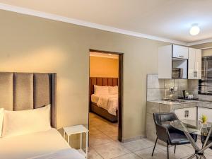 a bedroom with a bed and a table and a kitchen at Cosmo Sleepover in Roodepoort