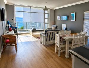 a living room with a table and chairs and a large window at 501 Beach Club in Mossel Bay