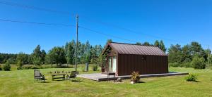 a small cabin with a table and chairs in a field at Rubīni in Jūrkalne +6 photos