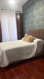 a bedroom with a bed with white sheets and floral wallpaper at Un Rincón en Alcalá in Alcalá de Henares