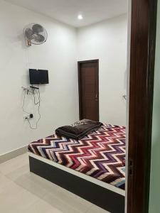a bedroom with a bed in a room with a fan at Sai Guest House in Pathānkot