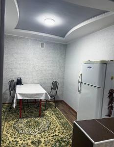 a dining room with a table and a refrigerator at Тихий дом in Fergana
