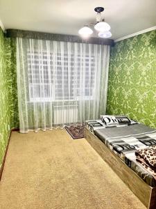a bedroom with green walls and a large window at Тихий дом in Fergana