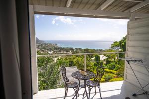 a balcony with a table and chairs and a view of the ocean at Wild Vanilla Apartment in Beau Vallon