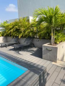 a swimming pool with two chairs and a palm tree at Executive Suites at The Lennox in Accra