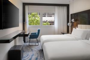 a hotel room with two beds and a television at Le Méridien Paris Arc De Triomphe in Paris