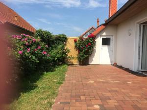a brick driveway leading to a white building with flowers at Ferienhaus 'Seeblick 39' in Glücksburg