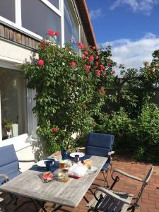 a table and chairs on a patio with roses at Ferienhaus 'Seeblick 39' in Glücksburg
