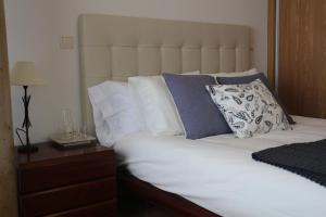 トレドにあるApartamento Homelife Toletumのベッド(白いシーツ、青い枕、ナイトスタンド付)