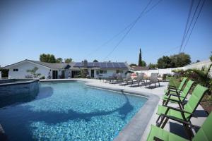 a swimming pool with green chairs and a house at Awesome 5 bedroom 3 bath pool home with in-ground jacuzzi in Orange