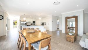 a dining room and living room with a wooden table and chairs at Blissful Birdsong Escape in Banksia Beach