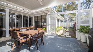 an outdoor dining room with a wooden table and chairs at Blissful Birdsong Escape in Banksia Beach